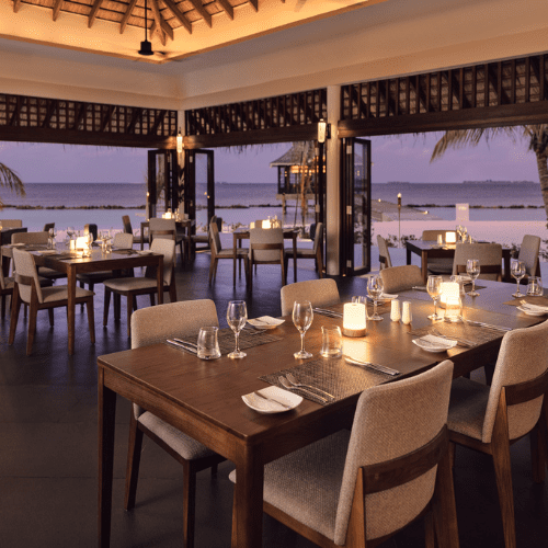 a restaurant with tables and chairs at sunset