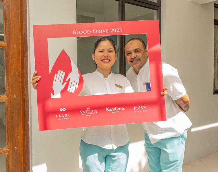 Nova staff holding a blood drive signage