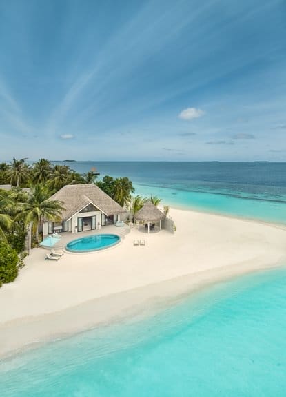 Aerial view of a beachfront villa with pool and clear waters