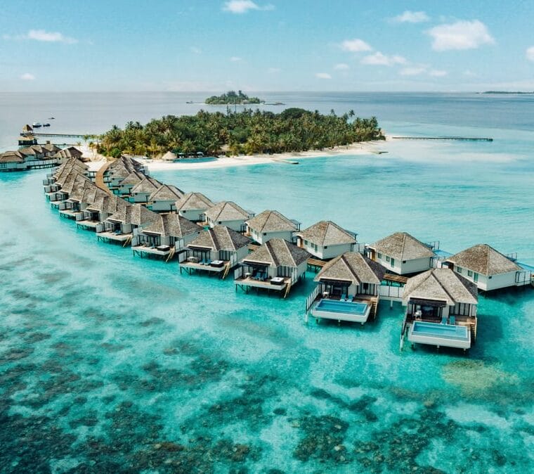 Stunning aerial view of overwater bungalows stretching into the turquoise ocean at a luxury resort.