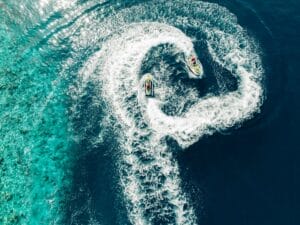 Two jet skis carving heart-shaped patterns in the sparkling turquoise ocean, reflecting an adventurous watersports experience.